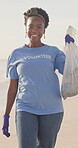 Woman, volunteer and plastic bag for environment cleaning as community activist, earth day or conservation. Black person, smile and trash on beach for recycling waste management, pollution or nature