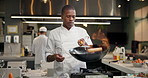 Chef, black man and pan on fire in kitchen for cooking with speed, professional and enhance flavor or taste. Person, serious and roast with flame for frying, gastronomy and culinary techniques.