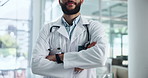 Man, hands and arms crossed as doctor in hospital for professional healthcare, cardiology or specialist. Male person, smile and confidence with stethoscope with work pride, life insurance or service
