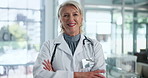 Mature, woman and doctor or face with arms crossed for healthcare or cardiology, stethoscope or professional. Female person, portrait and smile in hospital with life insurance, confidence or pride