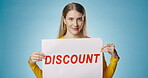 Woman, face and poster in studio for discount or clearance sale for retail or marketing for advertisement news. Girl, billboard and wink on blue background for fashion promotion sign and announcement