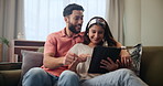 Happy, couple and relax on sofa with tablet for streaming videos, social media memes and entertainment. Man, woman and together in home with digital technology for search for new apartments in Mumbai