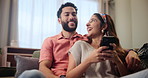 Happy, couple and relax on couch with smartphone for streaming videos, social media memes and entertainment. Man, woman and together in home with cellphone for research for new apartments in Mumbai.