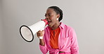 Megaphone, angry and black woman on gray background for protest, revolution and rights for equality. Communication, bullhorn and person shouting for information, announcement and speech in studio