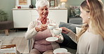 Senior woman, tea and toast in home with daughter for cheers, happy memory and care on visit in family home. Elderly mother, daughter and cheers on lounge couch with warm drink in talk for success