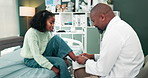 Happy doctor, child and tying shoes with checkup on bed for consultation, appointment or healthcare at clinic. Black man or medical employee helping girl tie laces at hospital or private practice