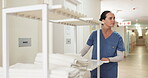 Hospital, clean and towels from laundry with nurse and cart for cloth, medical and hygiene with healthcare. Nursing home, hallway and caregiver with fabric for wellness, rehabilitation and uniform