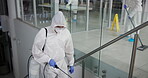 Man, hazmat suit and spray for cleaning at night, pandemic and disinfection for bacteria. Male person, lockdown and caution for illness spread on stairs, sanitation and biohazard for virus in office