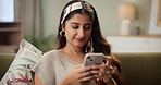 Indian woman, relax and sofa with phone for social media, communication or email in living room at home. Young female person typing and reading on mobile smartphone for online chatting or texting