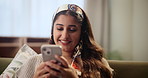 Indian woman, happy and relax with phone for social media, communication or browsing in living room at home. Young female person reading news with smile on mobile smartphone for online entertainment