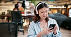 Woman, headphones and phone in cafe for search with technology, streaming music with app. Female student, mobile and earphones with scroll or typing for college, relax with audio at university