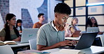 Male student, laptop and attention with typing in classroom for online, learning and development. African man, tech and people for education in group, exam or project at school, university or college