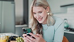 Smile, woman and typing with phone in kitchen with fruit for recipe on healthy, nutrition and detox juice in the morning. Happy, female person and reading online for smoothie for organic breakfast