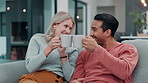Happy couple, talking and cheers with coffee in home living room for morning breakfast drink together. Man, woman and toast with tea for celebration, conversation and interracial people relax on sofa