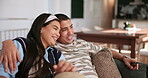 Couple, laughing and relax on sofa for television with remote, streaming service and watching tv in home. People, hug and entertainment with multimedia subscription, funny movie and bonding in lounge