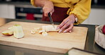 Person, hand and cutting banana fruit in kitchen for healthy diet or vegetarian snack, wooden board or knife. Nutrition, breakfast and morning ingredient or prepare lunch in home, organic or food