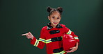 Face, firefighter and girl in uniform, pointing and happiness with youth on dark studio background. Portrait, model and kid with smile, career ambition or cheerful with joy, professional or promotion