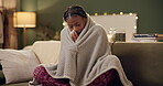 Woman, sick and tissue with blanket on sofa for blowing nose, recovery and winter virus in living room. African person, infection or ill with fever, sinus and allergy on couch in home with healthcare