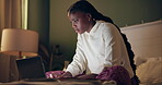 Laptop, night and student black woman on bed in home for distance learning or remote education. Computer, evening research and notebook with college or university person learning in apartment bedroom