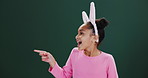 Easter, bunny and child pointing to surprise promotion, announcement in studio mockup. Holiday, sale and excited kid show crazy info in dark background, space for news with fashion or costume ears