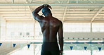 Neck, stretching and black man swimmer at pool for fitness,  training or water sports in gym. Back, exercise and health with warm up of professional athlete swimming for competition or wellness