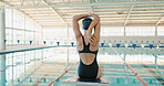 Swimming, back and woman with stretching by pool for cardio exercise, start and preparation. Athlete, practice and person with warm up at sports arena for fitness, training and muscle flexibility