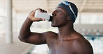 Black man, swimmer and drinking water at pool, hydration and break from workout or training. Male person, athlete and sports drink for thirst, mineral liquid and practice performance for competition