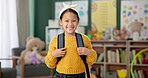 Child, face and smile in classroom with backpack for back to school excited with education, learning or youth. Girl, kid and happiness for first day as elementary student, scholarship or knowledge