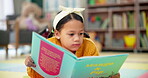 Girl, kindergarten and reading book in classroom, childhood development and growth for vocabulary in school. Calm, relaxing and knowledge or information with storybook, learning and fantasy for child