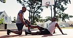 Injury, leg and stretching with friends on basketball court together for fitness, game or performance. Exercise, help and pain with black man sports people outdoor in summer for training or workout