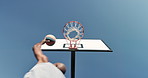 Basketball, hands and hoop from below with person outdoor on blue sky for sports practice or training. Exercise, fitness and health with athlete shooting ball to score for competition or game