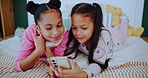 Young girls, smartphone and smile on bed for social media, entertainment or education at home. Happy, female sisters and mobile for streaming, learning or child development with cartoons in bedroom