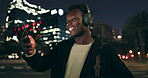 Black man, outdoor and dancing on smartphone with headphone for music playlist, entertainment at night in New York. Female person, happy and internet for streaming platform with song and video