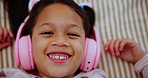 Headphones, smile and face of child on bed dancing to online music, radio or playlist at home. Happy, rest and portrait of girl kid streaming song or album on internet in bedroom at house from above.