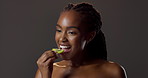 Beauty, eating orange slice and black woman in studio on dark background for dermatology or vitamin c. Food, skincare and smile with happy model biting citrus fruit for diet, health or nutrition