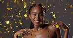 Woman, face and confetti skincare with smile for celebration in studio for surprise, cosmetics or brown background. Black person, happiness and beauty makeup with wellness, promotion or announcement