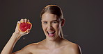 Grapefruit, squeeze and portrait of woman with skincare for natural beauty, vitamin c and cosmetics in studio. Dermatology, fruit and girl with confidence, smile or healthy skin on dark background.