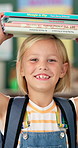 Balance books, school and face of girl ready for studying, lesson and learning in classroom. Textbooks on head,  student and portrait of happy, excited and young child for knowledge and education