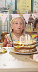 Girl, children and party with birthday cake at kindergarten, happy or celebration with confetti, friends and food. Kids, class and blow flame for wish, dessert and care for event at preschool academy