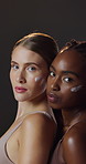 Skincare, moisturizer and face of interracial women in studio for natural, health and wellness routine. Beauty, portrait and friends with lotion, spf or sunscreen for dermatology by black background.