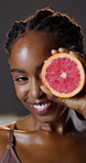 Grapefruit, beauty and portrait of black woman with skincare for natural vitamin c, benefits and cosmetics in studio. Dermatology, fruit and girl with facial, smile or healthy skin on dark background