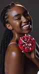 Skincare, face or happy woman in studio for pomegranate wellness, cosmetics or treatment on dark background. Smile, portrait or girl with fruit for collagen, sunscreen or antioxidant beauty benefits