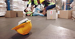 Engineer, team and injury with safety at warehouse in logistics, supply chain or distribution at depot. Group of employees helping colleague with helmet and boxes from fall or accident at storage