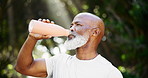 African man, running and drinking water on road with break for fitness, training and health in park. Senior person, bottle and hydration on street for detox, workout and thinking on path in summer