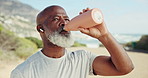 Senior African man, running and drinking water on road with earphones for music, training and fitness. Person, bottle and hydration on street for detox, workout and streaming subscription in summer