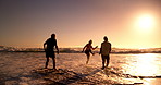 Beach, sunset and friends playing in waves on holiday, vacation and adventure together. Silhouette, summer and people laughing and splash by ocean for bonding, healthy relationship and fun outdoors