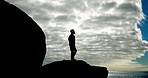 Thinking, person and silhouette with blue sky background and clouds for relax, peace and freedom. Man, shadow and  rocks with vision for success, goals and motivation on hike adventure for wellness