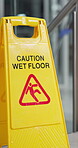 Wet floor, caution and warning with sign after cleaning, washing ground and housekeeping. Yellow plastic, attention and safety symbol for protection, slippery and alert for hygiene service in office