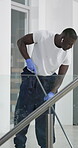 African man, cleaning and mopping office floor with earphones for work or company. Commercial cleaner, vertical and maintenance in workplace for sanitary environment, employees or staff with chemical