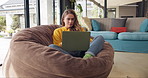 Relax, thinking and woman on bean bag with laptop, typing and reading on website for freelance career. Research, networking and girl in home with remote work, writing and computer for online job.